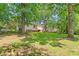 Residential backyard with lush green lawn, mature trees, back patio and storage shed on a sunny day at 422 Hyde St, Burlington, NC 27217