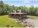Stunning, elevated log home with stone chimney, wraparound porch, and beautifully landscaped yard at 4659 Antioch Rd, Oxford, NC 27565
