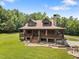 Charming log home with a porch, stone chimney, and lush green lawn at 4659 Antioch Rd, Oxford, NC 27565