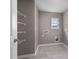 An empty laundry room features grey walls, tile flooring, a window, shelving and hook ups for a washer and dryer at 512 Providence Springs Ln, Fuquay Varina, NC 27526