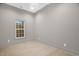 A minimalist bedroom with light hardwood flooring, gray walls, and a window at 516 Ottawa Ave, Durham, NC 27701