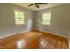 Relaxing bedroom featuring hardwood floors, ceiling fan, and bright windows at 5504 Balsam Pl, Raleigh, NC 27603