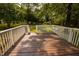 View of the wooden deck leading to a lush green yard with mature trees and a shed in the background at 5504 Balsam Pl, Raleigh, NC 27603