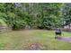 Backyard view showcasing an open lawn area, mature trees, a wooden fence and a BBQ grill at 5817 Seward Dr, Knightdale, NC 27545