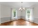 Bright dining area with hardwood floors, a chandelier, and large windows adorned with sheer curtains at 6411 Pondview Ln, Durham, NC 27712