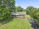Aerial view of a brick home with a well-kept lawn, mature trees, and a long driveway at 6411 Pondview Ln, Durham, NC 27712