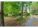 View of a well-maintained yard with a charming home exterior and gravel driveway at 7 Woodward Way, Chapel Hill, NC 27516