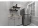 Wet bar area featuring a geometric wallpaper, floating shelves, white cabinets, and stainless steel fridge at 7000 Millstone Ridge Ct, Raleigh, NC 27614