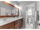 Bathroom featuring double sinks, wood cabinets, and a view into a tiled toilet and shower room at 7000 Millstone Ridge Ct, Raleigh, NC 27614