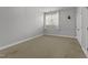 Bedroom with neutral walls, carpet, a window with curtains, a plant, and an entry door at 7000 Millstone Ridge Ct, Raleigh, NC 27614