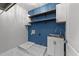 Bright laundry room featuring stainless steel sink, white cabinets, open wood shelving, and marble tiled floors at 7000 Millstone Ridge Ct, Raleigh, NC 27614