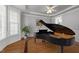 Elegant living room featuring a grand piano, hardwood floors, and beautiful natural light at 7000 Millstone Ridge Ct, Raleigh, NC 27614