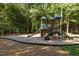 Community playground featuring slides, climbing structures, and swings amidst a wooded area at 7000 Millstone Ridge Ct, Raleigh, NC 27614