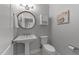 Charming powder room with a pedestal sink, round mirror, and decorative seashell artwork at 7000 Millstone Ridge Ct, Raleigh, NC 27614