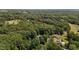 A home blends with a golf course and verdant woods in an aerial landscape at 825 Whispering Wind Rd, Burlington, NC 27217