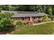 Brick home with well-maintained lawn and landscaping, complemented by solar panels on the roof at 825 Whispering Wind Rd, Burlington, NC 27217