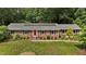 Charming brick ranch home with a red front door, lush landscaping, and solar panels at 825 Whispering Wind Rd, Burlington, NC 27217