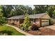 Well-manicured brick home with attached garage and lush, mature landscaping at 825 Whispering Wind Rd, Burlington, NC 27217