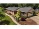 Aerial view showing a brick home, mature landscaping, and a two car garage at 825 Whispering Wind Rd, Burlington, NC 27217