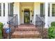 Inviting front porch with brick steps, black railings, and white pillars at 877 Millcroft, Pittsboro, NC 27312