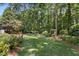 Spacious backyard showcasing a lush lawn and wooded area with various trees and foliage at 103 Saint Brides Ct, Cary, NC 27518