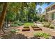 Lush backyard features a patio with outdoor seating, raised garden beds, and mature trees at 103 Saint Brides Ct, Cary, NC 27518