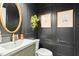 Stylish powder room featuring dark paneled walls, an oval mirror, and modern fixtures at 103 Saint Brides Ct, Cary, NC 27518