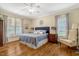 Primary bedroom with wood floors, a ceiling fan and a large bed with a blue quilt and decorative pillows at 10809 Grassy Creek Pl, Raleigh, NC 27614