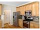 A stainless steel refrigerator and range complement light wood cabinets and a mosaic backsplash in this kitchen at 10809 Grassy Creek Pl, Raleigh, NC 27614