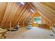 Unfinished attic space with exposed wooden beams, storage shelves, and a window for natural light at 1084 Wild Briar Ln, Stem, NC 27581