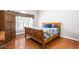 Warm bedroom features hardwood floors, a wooden bed frame, and natural light from the window at 1084 Wild Briar Ln, Stem, NC 27581