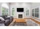 Bright living room with a fireplace, arched windows, and stylish gray sofas at 1084 Wild Briar Ln, Stem, NC 27581