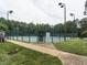 Well-maintained tennis court enclosed by a fence, featuring lighting for evening play in a landscaped setting at 109 N Fern Abbey Ln, Cary, NC 27518