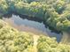 Aerial view showcasing a picturesque lake surrounded by lush, green trees and a serene natural setting at 110 Wolfs Trl, Chapel Hill, NC 27516