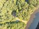Aerial view of a brown roofed house near a calm lake surrounded by verdant trees on a sunny day at 110 Wolfs Trl, Chapel Hill, NC 27516
