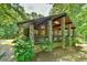 Stunning exterior elevation of a cabin-style home featuring stone pillars and a cozy porch area surrounded by lush trees at 110 Wolfs Trl, Chapel Hill, NC 27516
