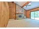 Spacious living room featuring a stone fireplace, wood paneled walls, ceiling beams, and a sliding glass door at 110 Wolfs Trl, Chapel Hill, NC 27516
