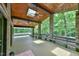 Spacious covered porch featuring stone columns, a wooden ceiling with fans, and scenic views of the wooded surroundings at 110 Wolfs Trl, Chapel Hill, NC 27516