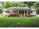 Charming single-story home with brick foundation, cozy front porch, lush lawn, and mature trees at 117 Lema Dr, Garner, NC 27529