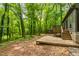 View of backyard showing deck with steps leading to a large area surrounded by mature trees and landscaping at 120 Polks Landing Rd, Chapel Hill, NC 27516