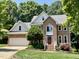 Beautiful two-story brick home boasts a well-manicured lawn and lush landscaping with mature trees at 122 N Fern Abbey Ln, Cary, NC 27518
