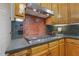 Kitchen boasts a cooktop, stainless steel hood, wood cabinets, and red tile backsplash at 122 N Fern Abbey Ln, Cary, NC 27518