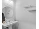 Stylish powder room with a pedestal sink, round mirror, and modern shelving at 1230 S 2Nd St, Smithfield, NC 27577