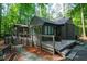 The house has a gray exterior, a large deck and is surrounded by lots of green trees at 128 Shadowbrook, Pittsboro, NC 27312