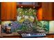 This kitchen is equipped with a unique mosaic backsplash and stainless steel stove top with granite counters at 128 Shadowbrook, Pittsboro, NC 27312