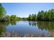 Picturesque pond reflecting the surrounding greenery under a clear blue sky, offering a tranquil natural setting at 128 Shadowbrook, Pittsboro, NC 27312