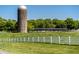 Picturesque farm view featuring a silo and white picket fence against a backdrop of lush greenery and clear blue sky at 128 Shadowbrook, Pittsboro, NC 27312