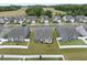 Aerial view of backyards in a well-manicured neighborhood, highlighting white fences, grass and neighboring homes at 129 Alumroot Rd, Holly Springs, NC 27540