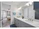 Bathroom vanity with double sinks, gray cabinets, quartz countertop, and view to the bedroom at 129 Alumroot Rd, Holly Springs, NC 27540