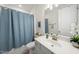 A clean and bright bathroom featuring a sink vanity, a mirror, and a shower with a blue curtain at 129 Alumroot Rd, Holly Springs, NC 27540